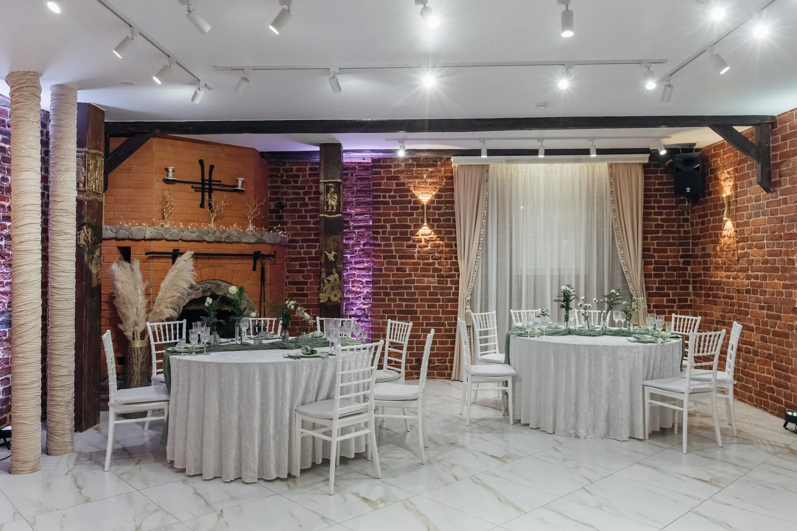 Каминный зал: Камин, круглые гостевые столы и зелёный текстиль